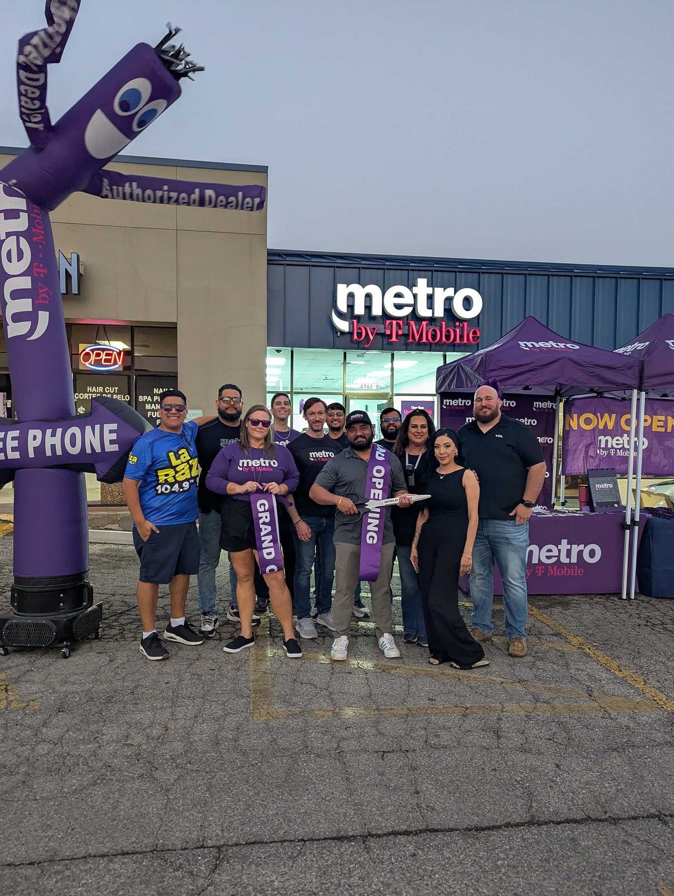 A street team in branded shirts standing outside a store beside a pop-up tent and an inflatable tube figure.