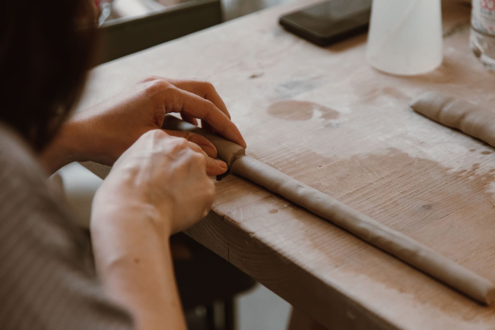 A pair of hands working a length of timber flat on a workbench.