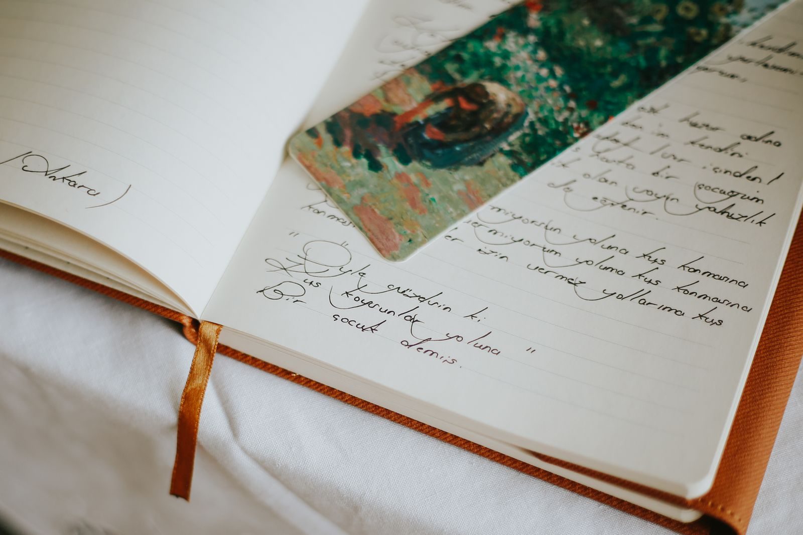 An open notebook filled with handwriting, a ribbon marker laid across the page.