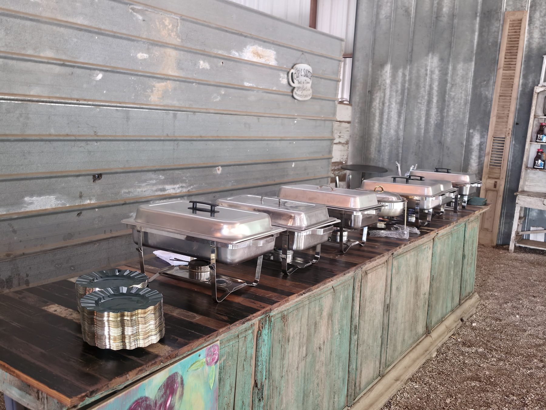 A row of chafing dishes set up along a reclaimed timber bar, ready for service.