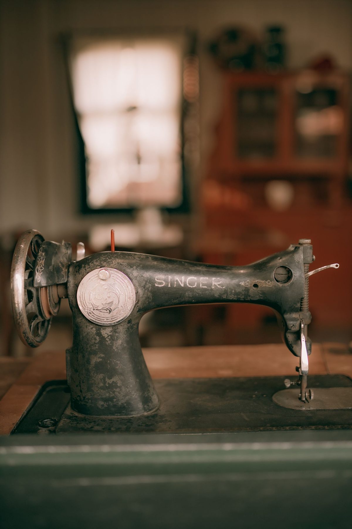 An old treadle sewing machine standing on a wooden bench.