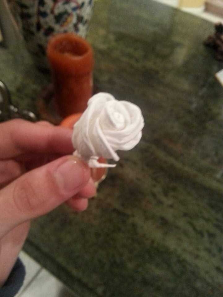 A rose folded from paper, held between finger and thumb.